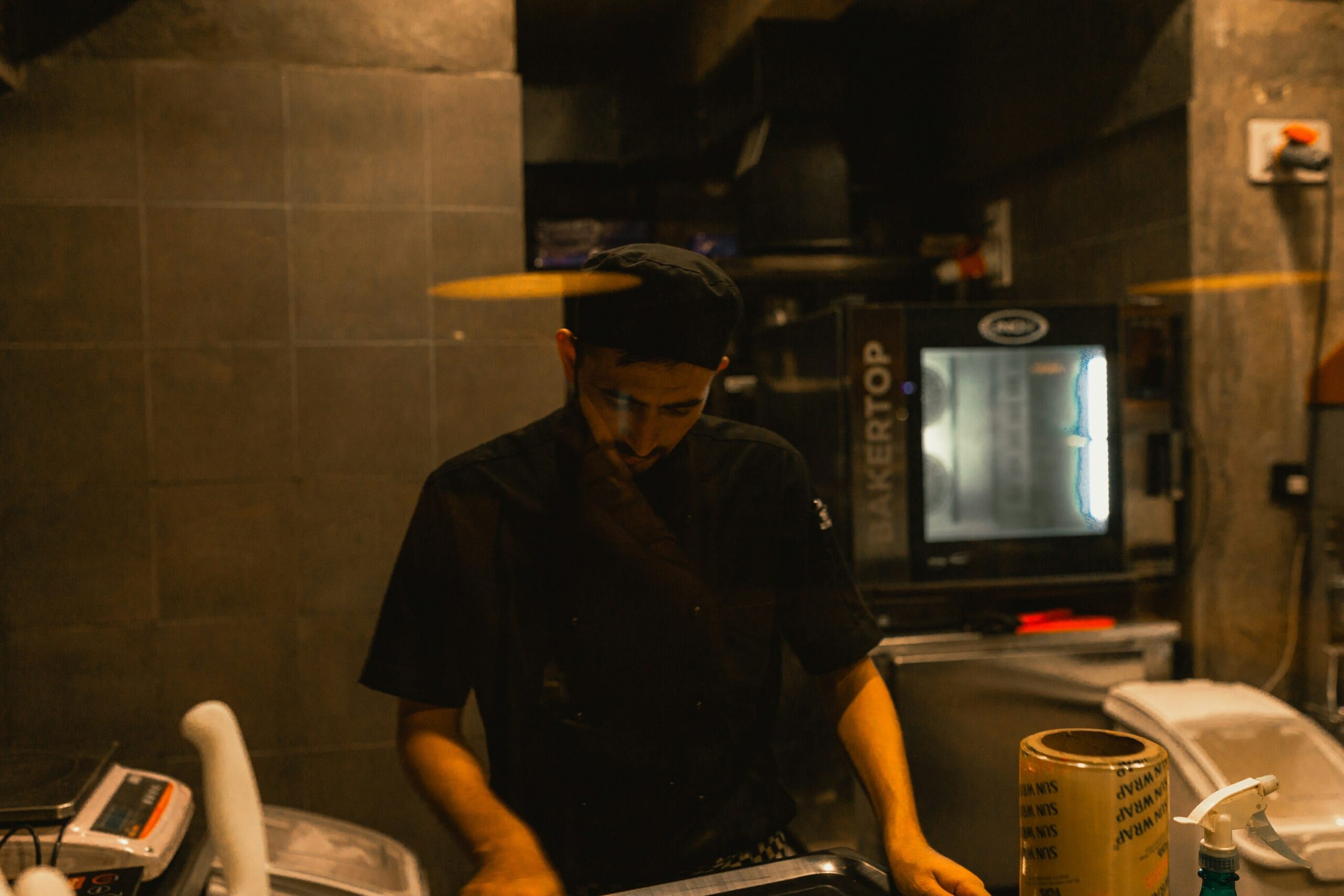 Secret Supper Clubs : A chef plating dishes in an open kitchen during an exclusive underground dining event.