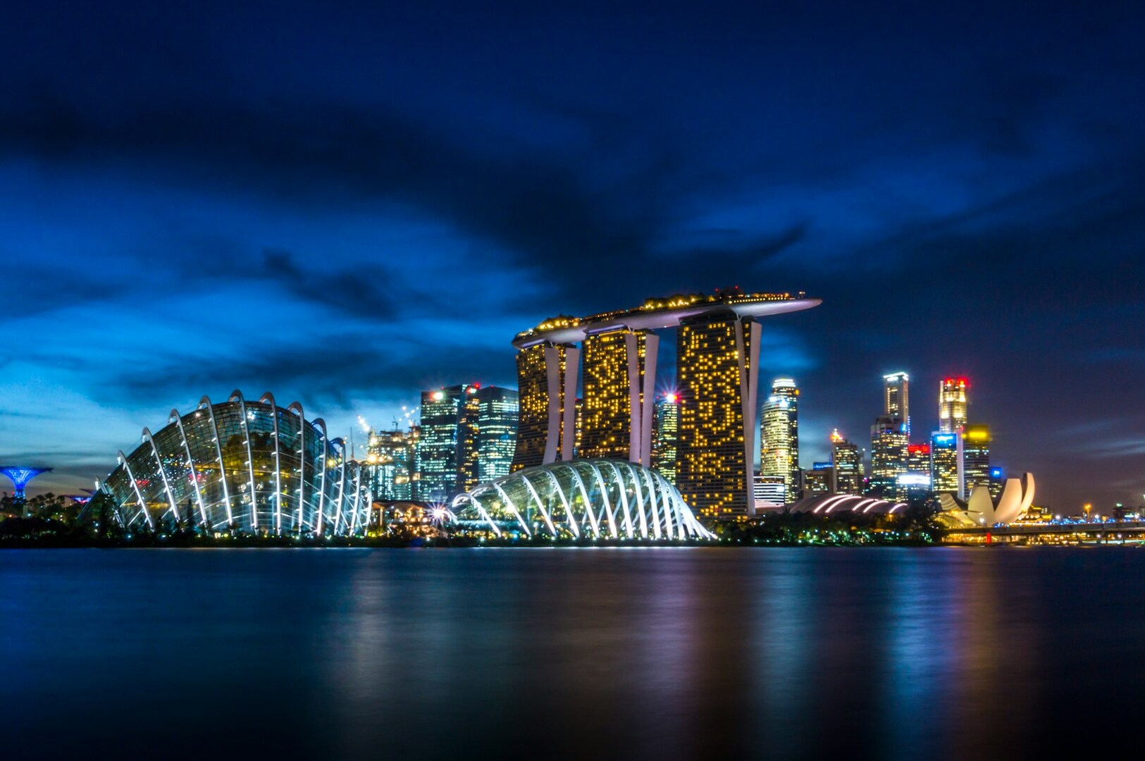 Night view of Singapore's skyline, illuminated buildings reflecting on the water, highlighting a popular photography spot.