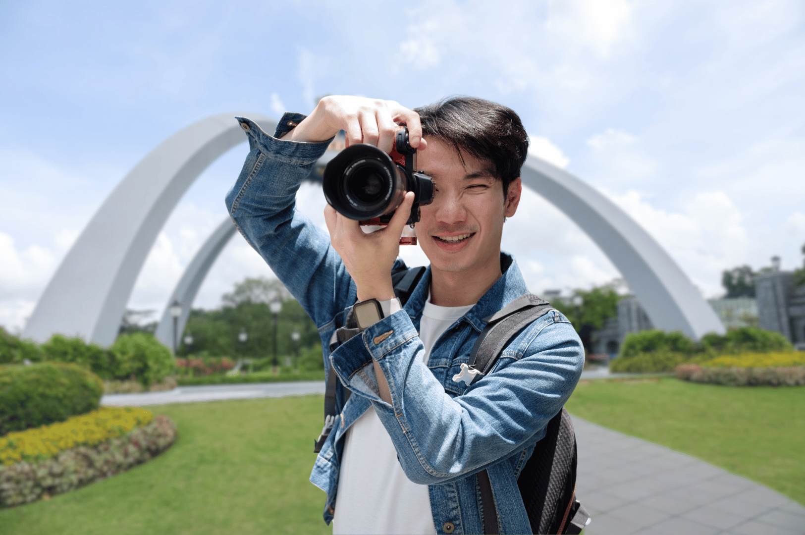 Photographer capturing the moment at a scenic Johor Bahru park with white arches and lush greenery—reflecting the city’s visual charm and appeal to culture-seeking day trippers.