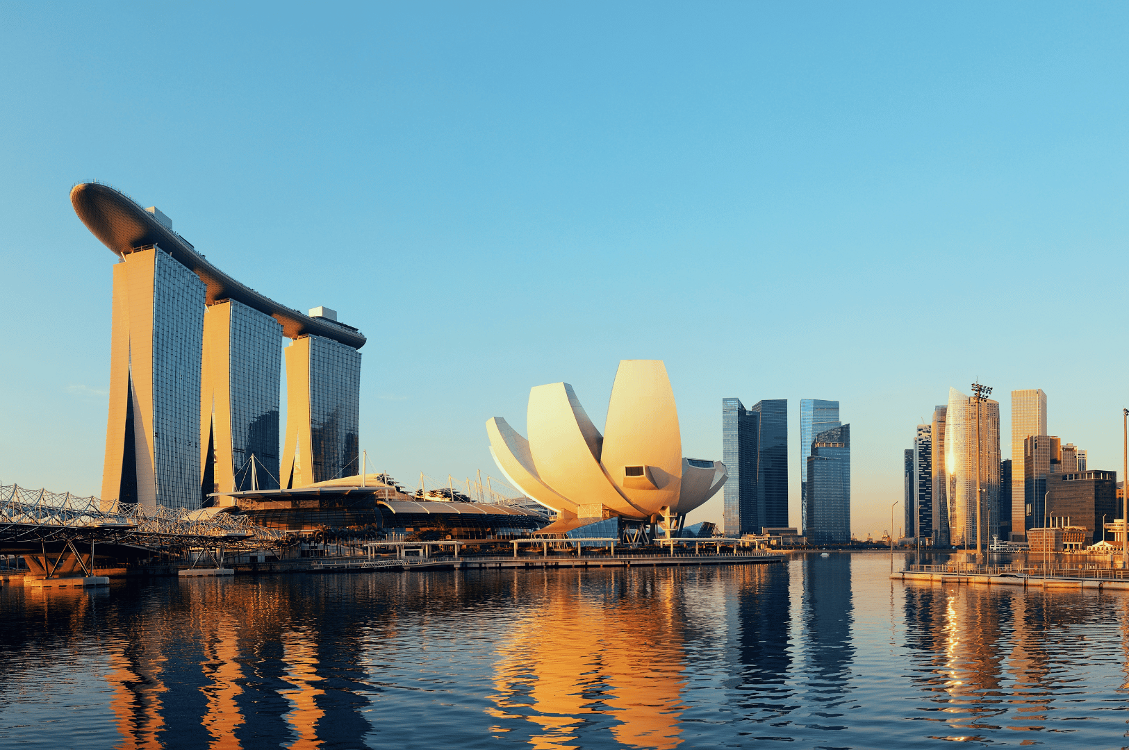 Marina Bay Sands gleams under a clear blue sky, its ship-like sky park bridging three towers above the calm waters of Marina Bay, while the lotus-shaped ArtScience Museum anchors the scene—an awe-inspiring urban vista that invites families to explore Singapore’s imaginative attractions beyond the thrill rides of Universal Studios.