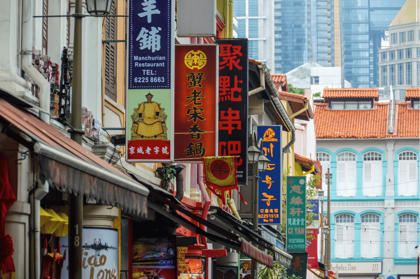 A bustling Chinatown street in Singapore lined with colorful shophouses and Chinese restaurant signboards, blending traditional heritage architecture with modern skyscrapers in the background—capturing the cultural vibrancy of the Lion City in a weekend itinerary.