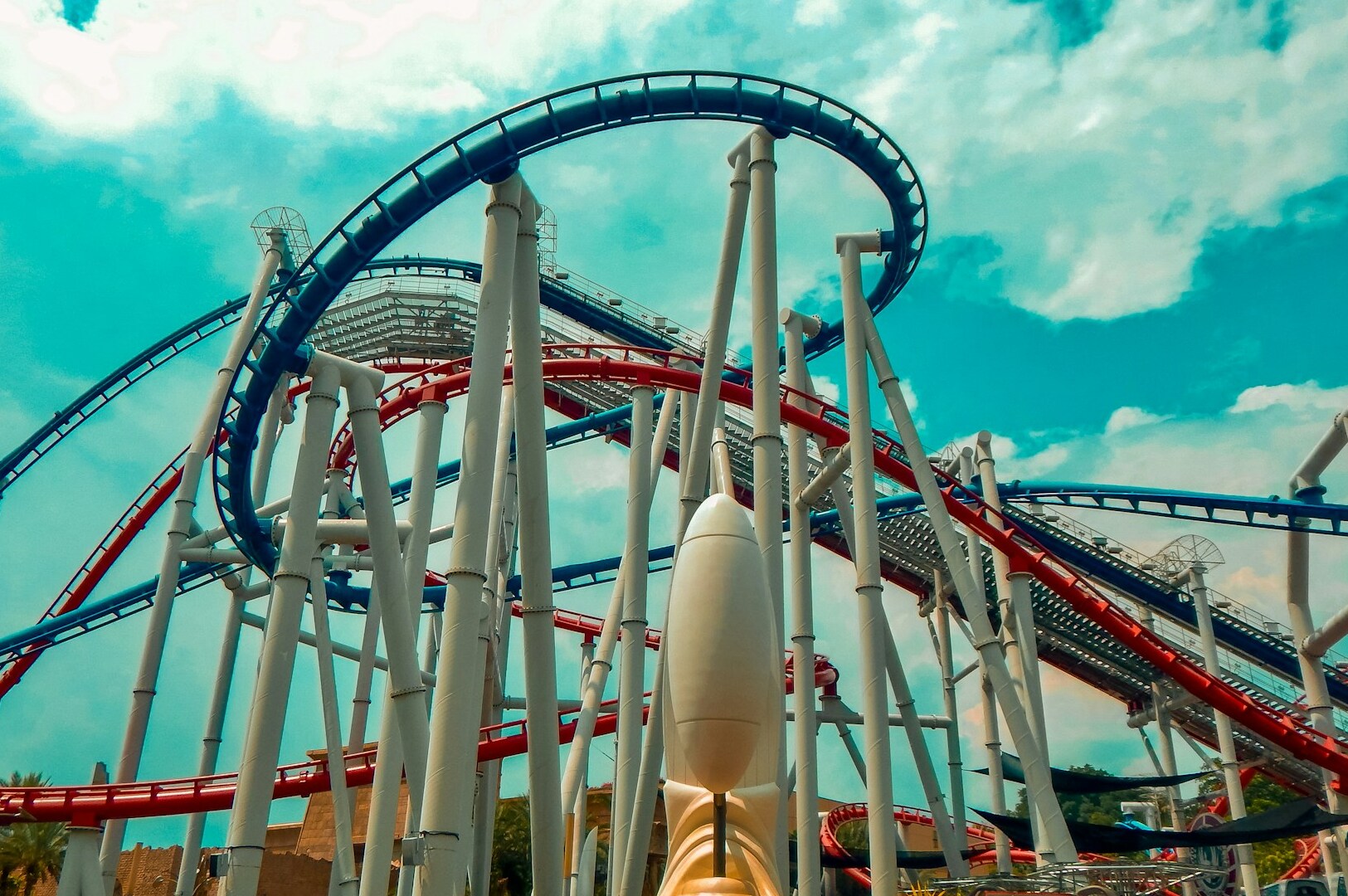 Universal Studios Singapore roller coaster topped with a rocket, twisting and turning against a vibrant universal studios theme park.