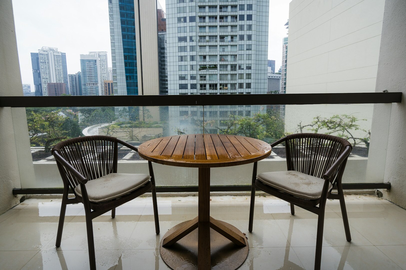 Balcony at Hilton Singapore Orchard featuring two chairs and a table, ideal for relaxation and enjoying the view.