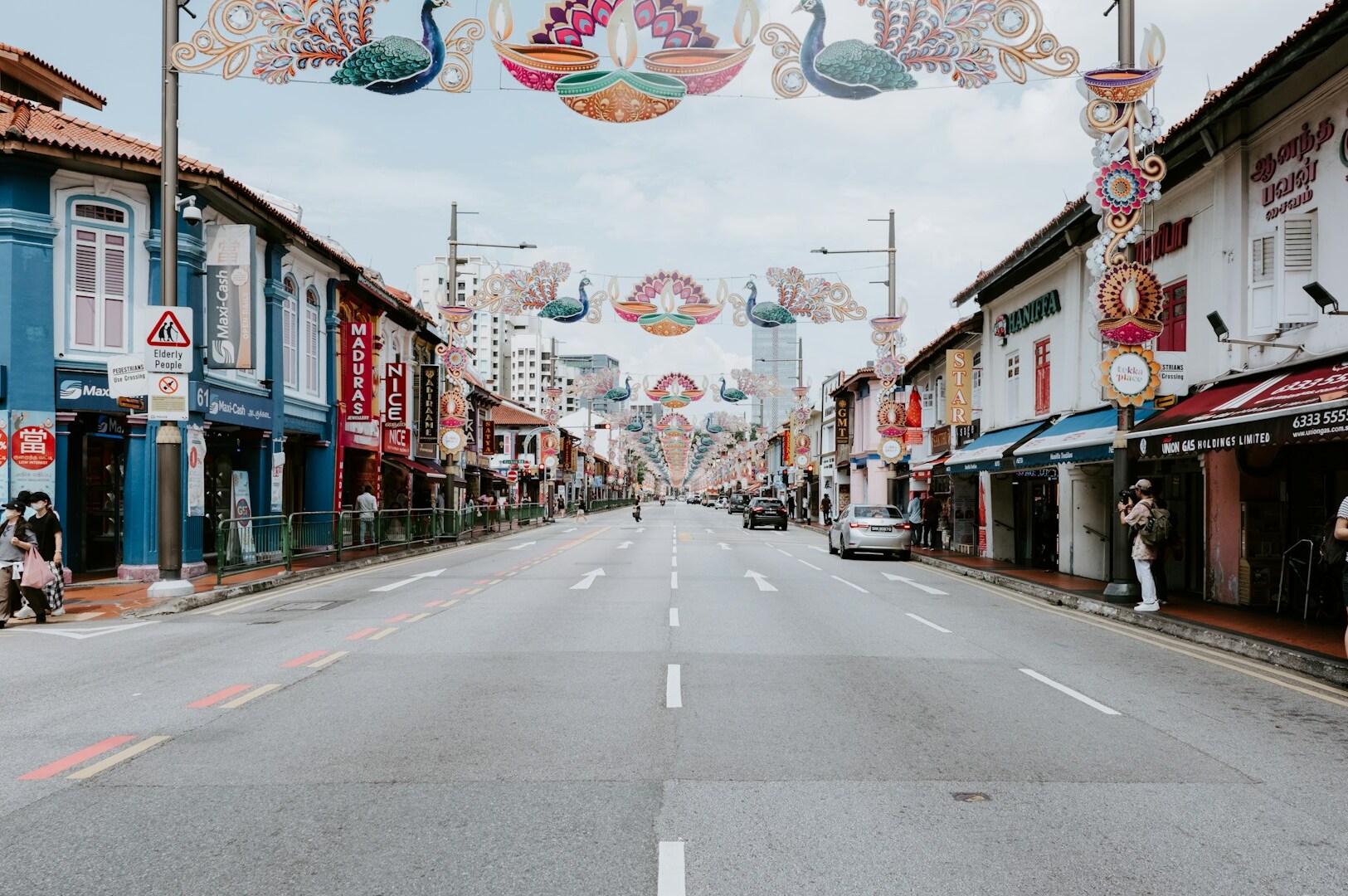 Colorful decorations line a street in Little India, Singapore, as a car travels down the lively thoroughfare.