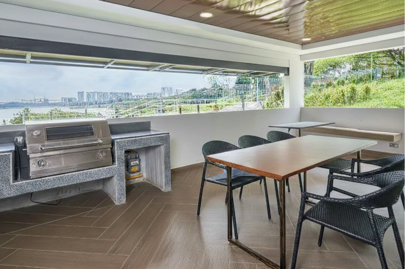 An outdoor covered patio featuring a built-in stainless steel BBQ grill and a dining table with black wicker chairs.