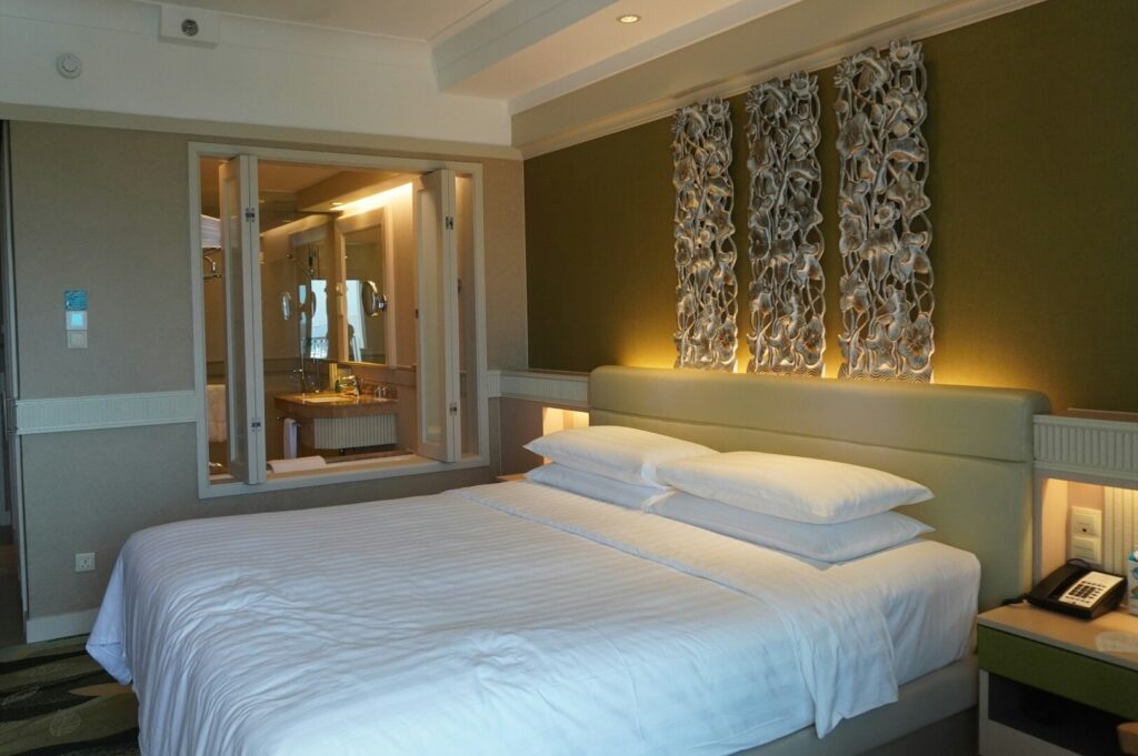 Modern hotel room with a cozy bed, telephone, and a mirror, showcasing the Best New Hotels in Sentosa.