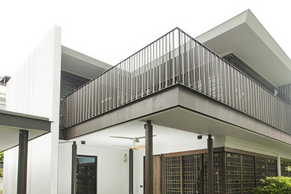 A modern architectural structure in Singapore, characterized by a clean, minimalist design with sharp white lines, dark wood-framed lattice windows, and a large, partially covered outdoor terrace area featuring a black metal railing and ceiling fans.