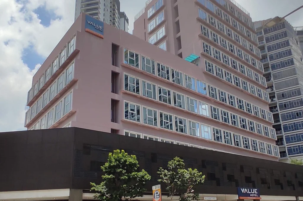 The exterior of Value Hotel Thomson in Singapore, showcasing its tall, modern building with a clean white and grey facade. The hotel features rows of uniform windows and prominent "Value Hotel" signage at the top
