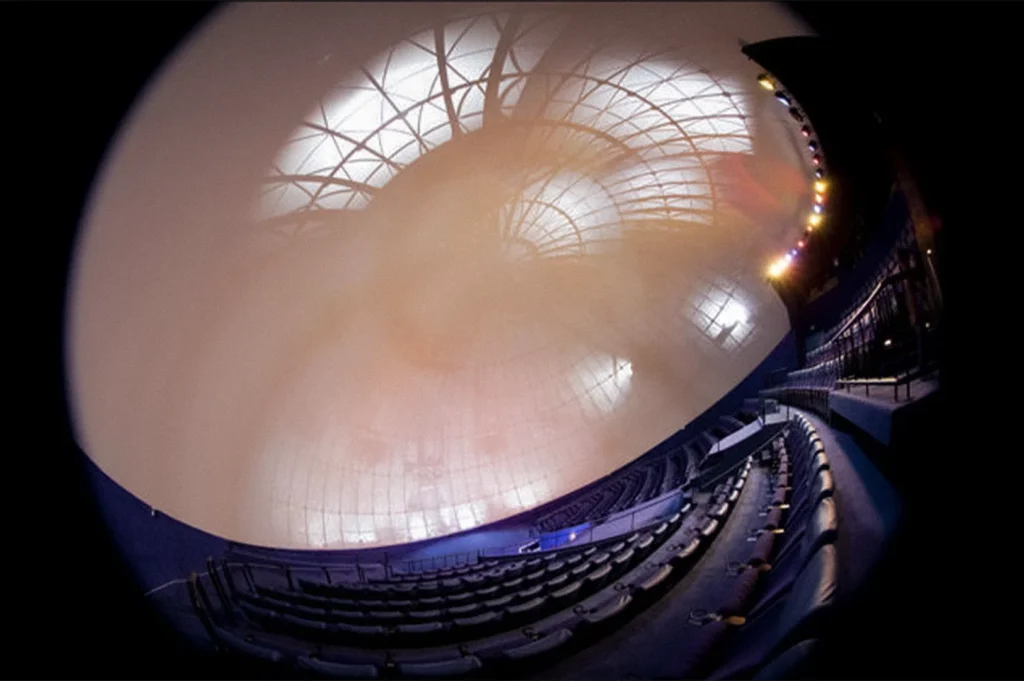 Wide-angle interior view of the Omni-Theatre at Singapore Science Centre featuring the massive domed screen, curved seating rows, and illuminated ceiling structure inside the immersive cinema auditorium