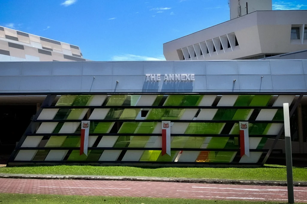 The Annexe building at Science Centre Singapore featuring modern geometric glass panels, contemporary architecture, and landscaped outdoor surroundings under a clear blue sky