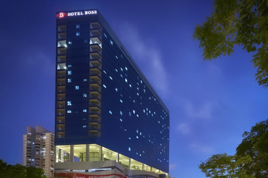 Night view of Hotel Boss in Lavender, Singapore, showcasing a modern high-rise facade with illuminated windows, sleek architecture, and city surroundings under a twilight sky.