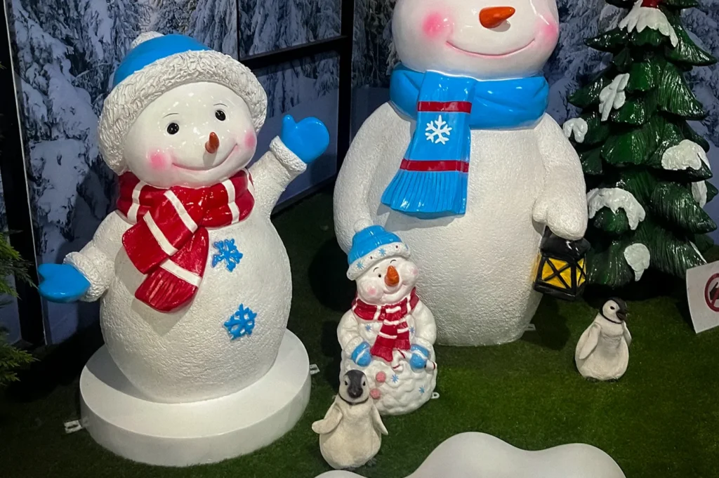 Snowman family display at Snow City Singapore in the Science Centre featuring festive winter decorations, penguin figures, and snowy forest backdrop indoors