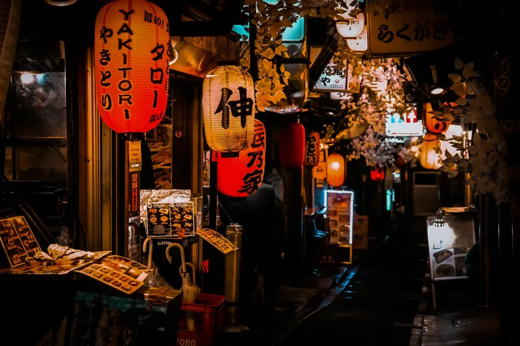 Japanese-style izakaya bar in Singapore with glowing paper lanterns, cozy alleyway seating, authentic restaurant signage, and a vibrant nightlife atmosphere.
