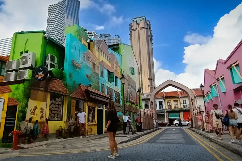 Colorful street art and heritage shophouses along Arab Street in Singapore, featuring vibrant murals, historic architecture, pedestrians, and a lively cultural atmosphere near Kampong Glam.