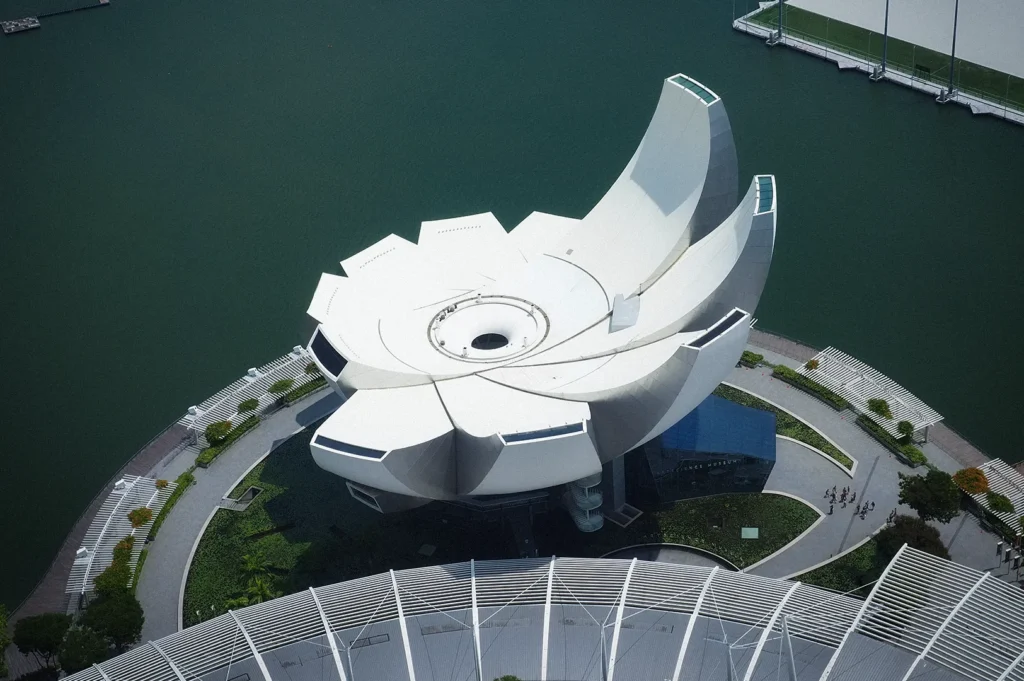 Aerial view of the ArtScience Museum in Singapore’s Marina Bay, showcasing its iconic lotus-inspired architecture surrounded by waterfront promenades and modern city landmarks.