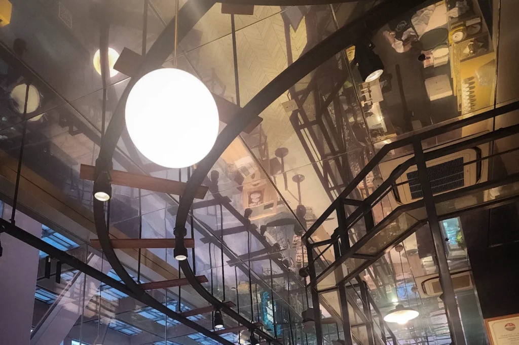 Interior of Japan Rail Cafe Singapore featuring a high glass ceiling, modern industrial architecture, hanging globe lights, and a spacious Japanese-inspired cafe setting with counter seating and dining areas.