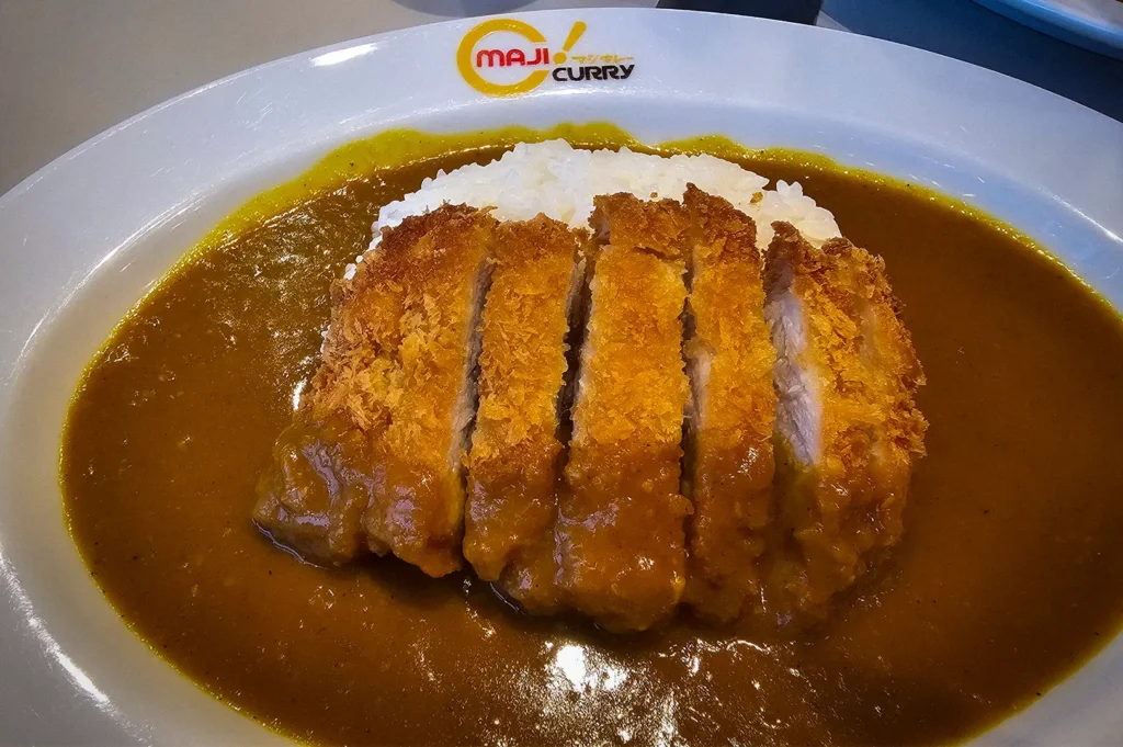 Golden crispy tonkatsu served over steamed rice with rich Japanese curry sauce at Maji Curry Singapore, showcasing a popular comfort food favorite.