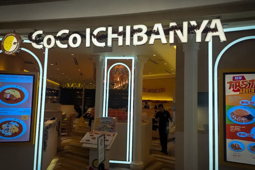 CoCo Ichibanya restaurant entrance with illuminated signage, digital menu boards, and modern Japanese curry dining interior in Singapore.