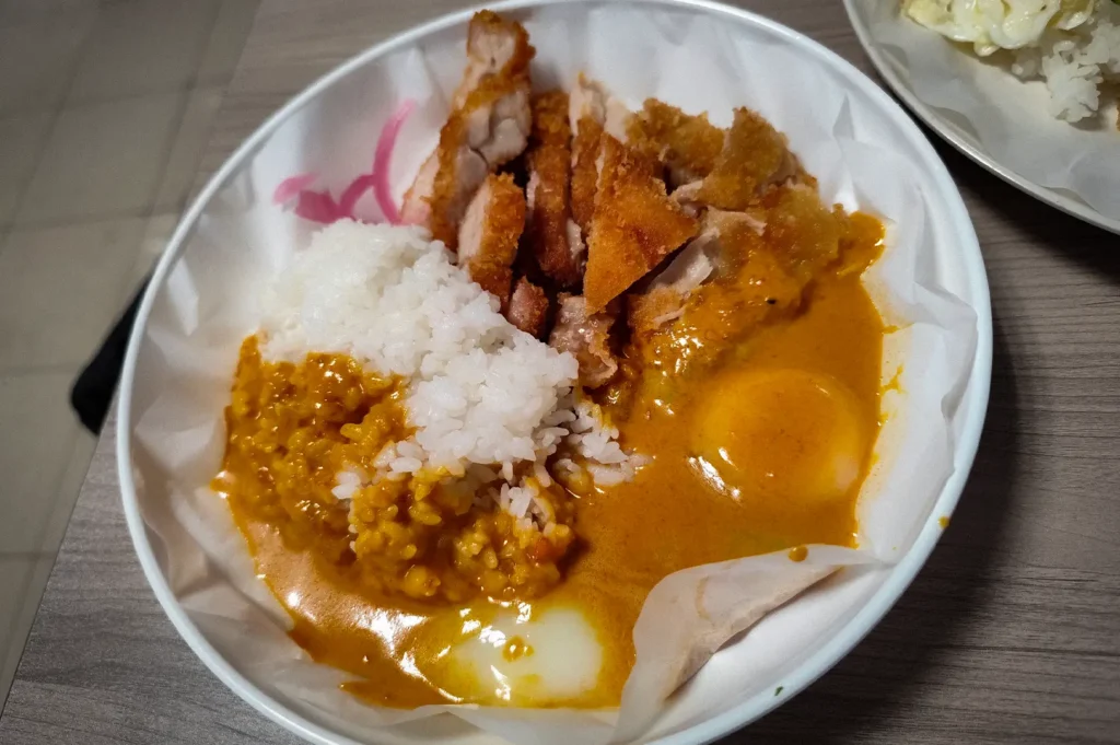 Chloe's Style Curry Chicken Cutlet Rice with onsen egg from New Station Rice Bar, served with crispy chicken cutlet, steamed rice, rich curry sauce, and pickled onions.