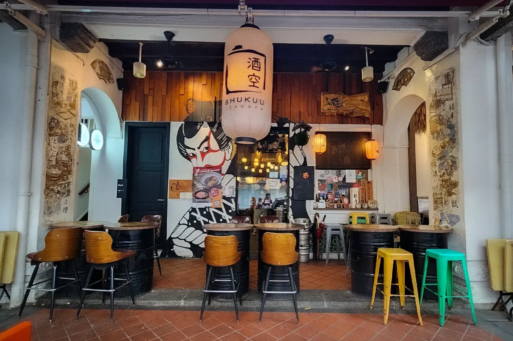 Front entrance of Shukuu Japanese Izakaya Singapore featuring traditional Japanese lanterns, outdoor seating, heritage shophouse architecture, and a welcoming izakaya façade in Chinatown.