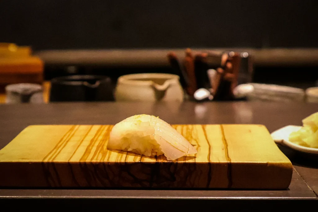 Single piece of premium Japanese nigiri sushi served on a wooden board at an omakase counter, highlighting minimalist presentation and fine dining craftsmanship.