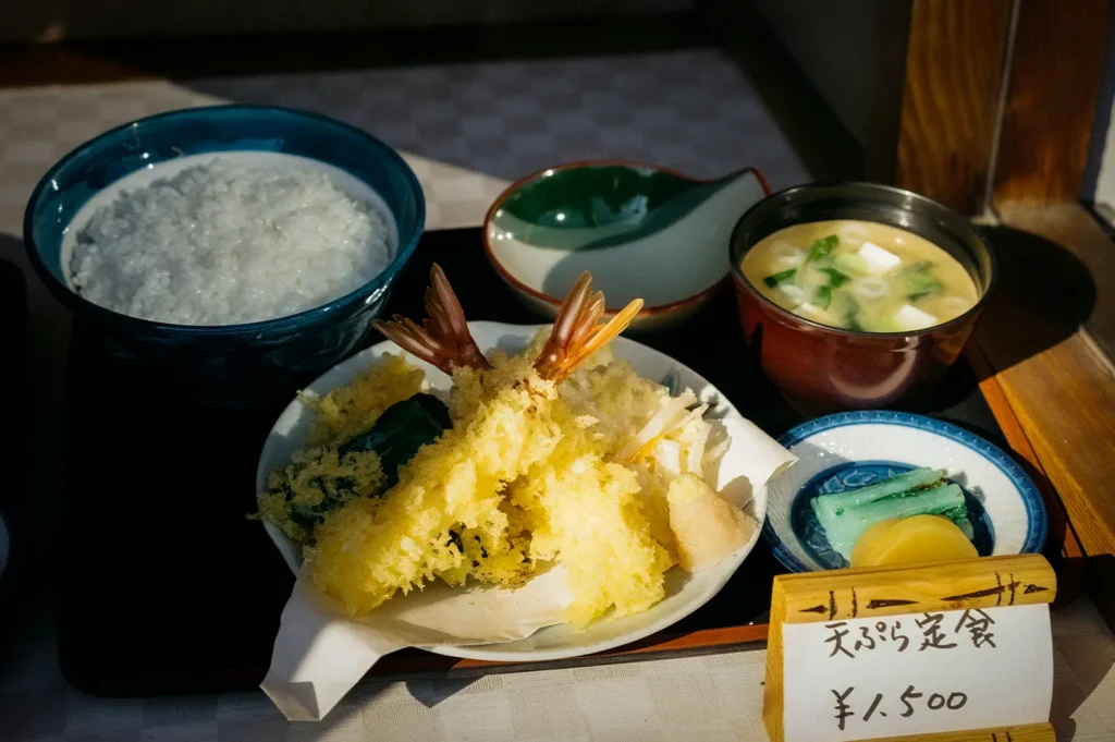 Traditional Japanese tempura set meal with crispy shrimp and vegetable tempura, steamed rice, miso soup, pickles, and dipping sauce served on a tray.